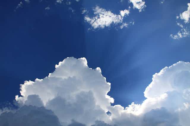 A blue sky with a fluffy cumulonimbus cloud obscuring the sun.