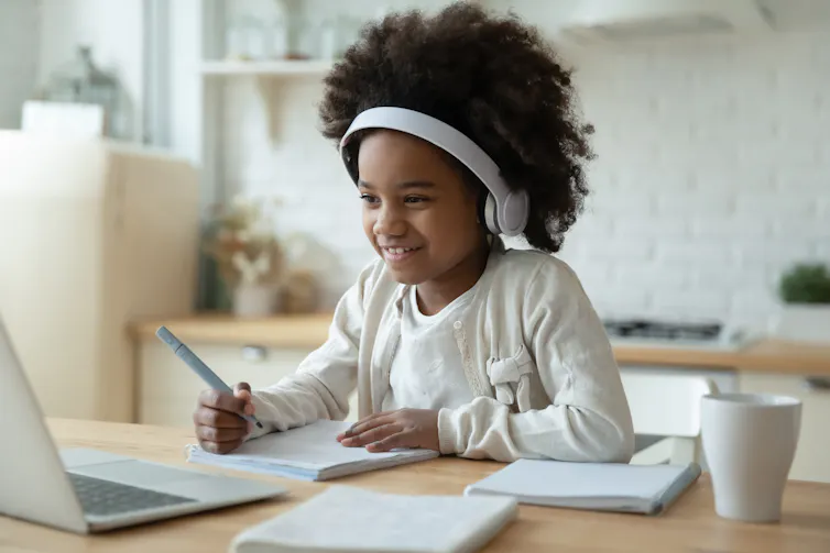 A child wearing headphones at a laptop.