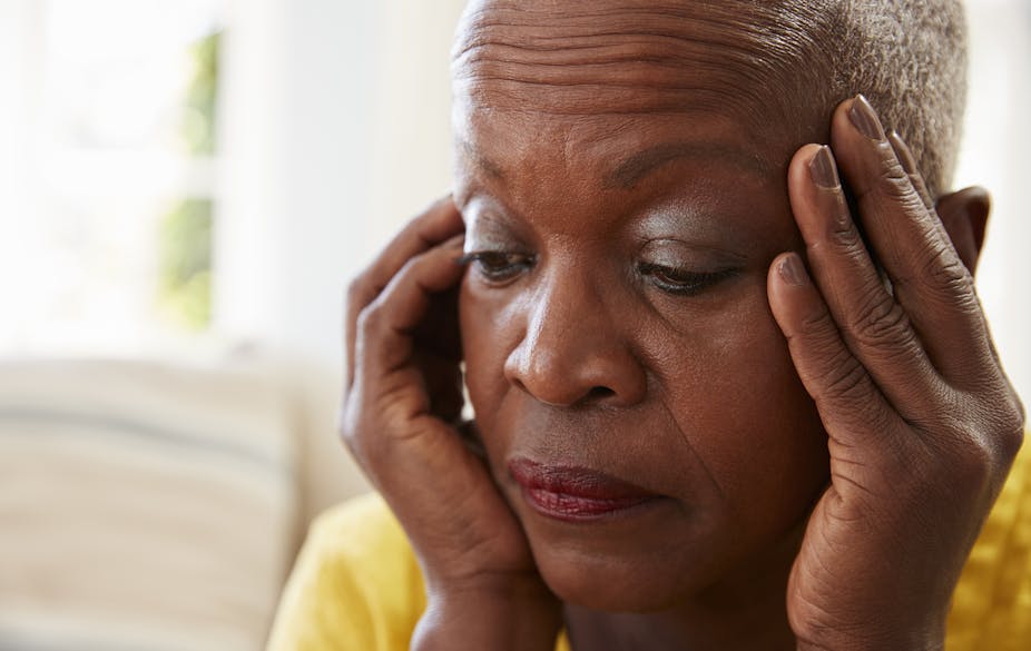 An older Black woman with her hands to her face.