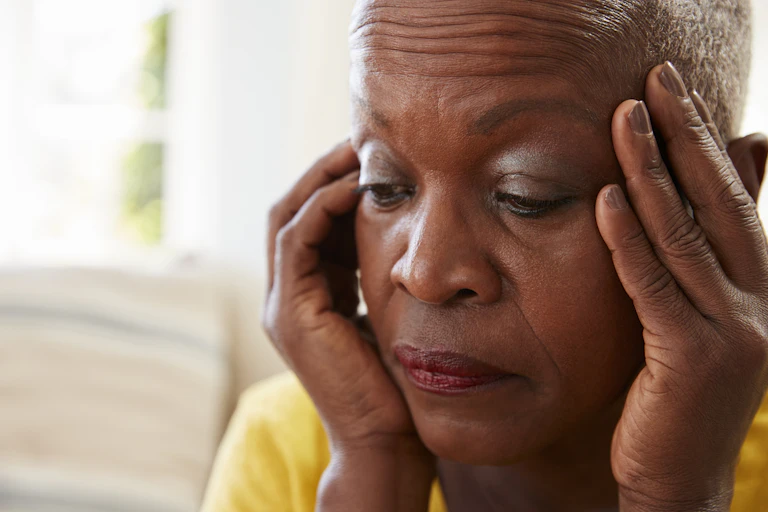 An older Black woman with her hands to her face.