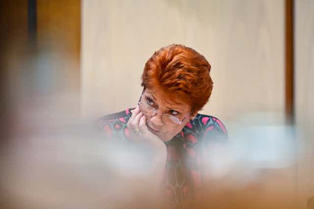 Pauline Hanson resting her head in her hand, with serious expression