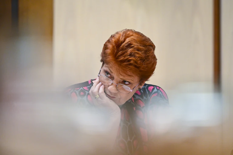 Pauline Hanson resting her head in her hand, with serious expression