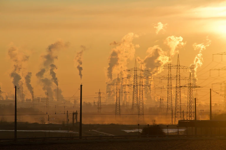 Electrical towers with smoke rising in the background