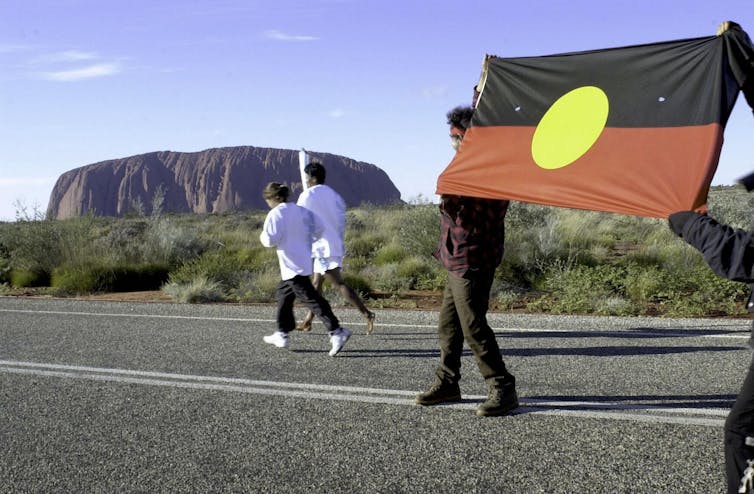The Olympic torch is carried past Uluru