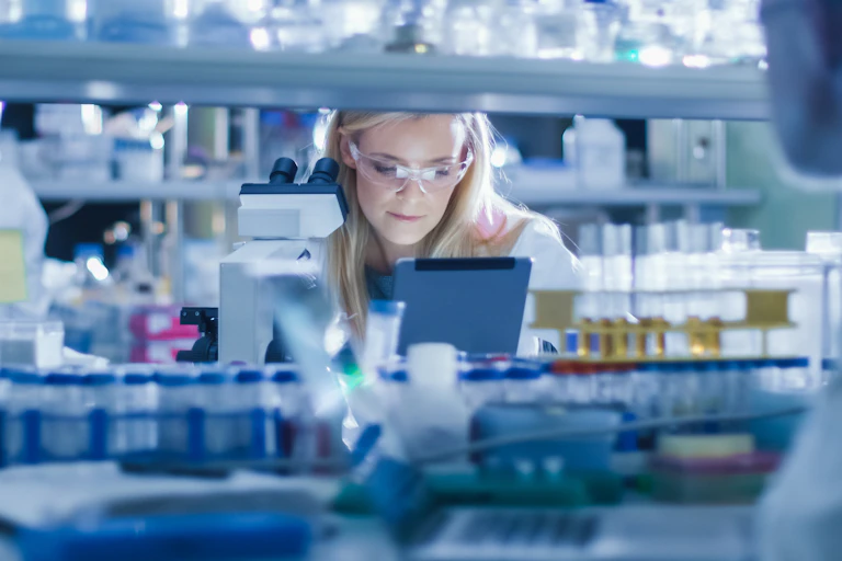 A woman in a science lab looking at a tablet screen.