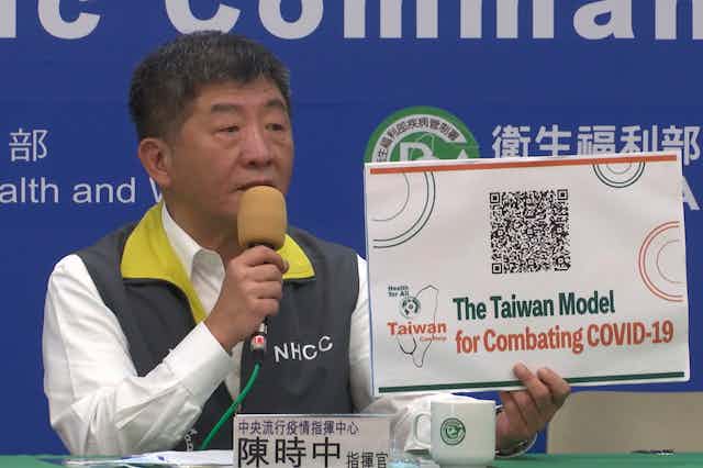 Taiwan's Health Minister Chen Shih-chung holds a sign reading 'The Taiwan Model for Combating COVID-19'.