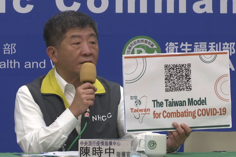 Taiwan's Health Minister Chen Shih-chung holds a sign reading 'The Taiwan Model for Combating COVID-19'.