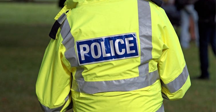 A police officer wearing a neon yellow jacket that reads 'POLICE.'