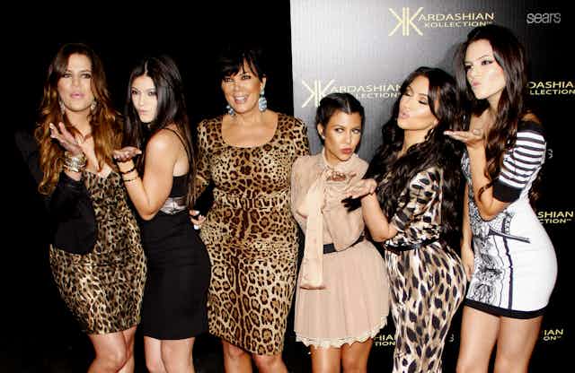 Six Kardashians wearing mostly leopard print on a red carpet.