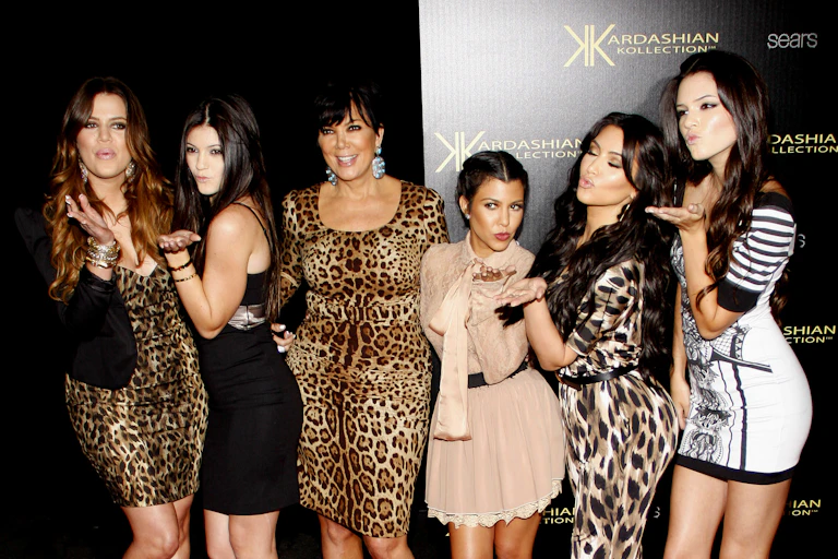 Six Kardashians wearing mostly leopard print on a red carpet.