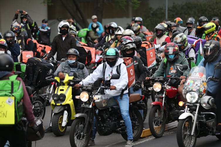 Large group of delivery drivers on scooters and motorbikes.