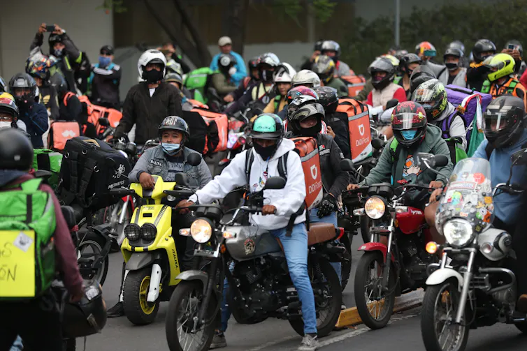 Large group of delivery drivers on scooters and motorbikes.