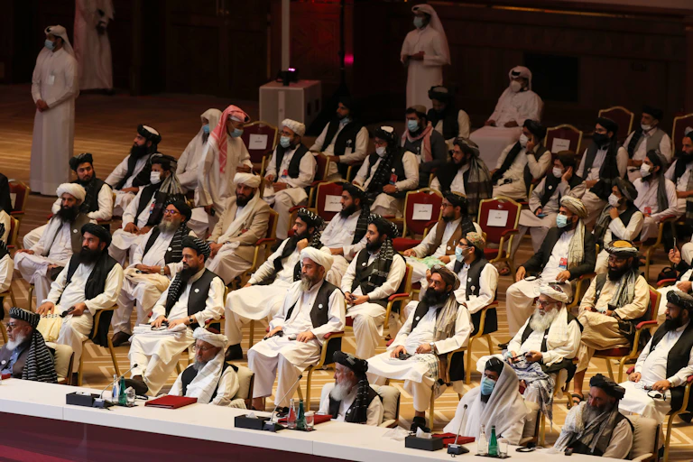 Dozens of Taliban members sit in an auditorium-style setting