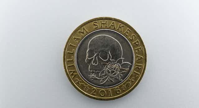 A coin showing a skull and rose. 