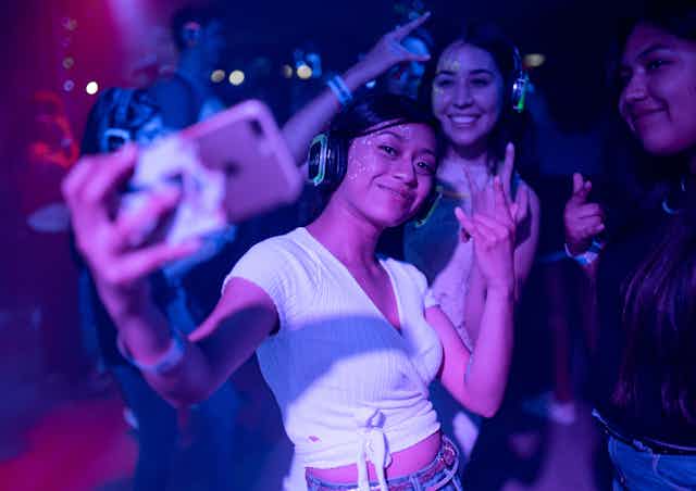 Three young women dancing and taking a selfie at a nightclub.