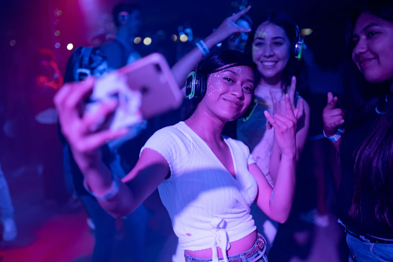 Three young women dancing and taking a selfie at a nightclub.