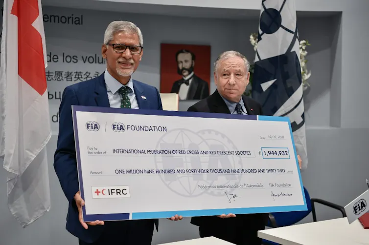 Le secrétaire général de la Fédération internationale des sociétés de la Croix-Rouge et du Croissant-Rouge (FICR), Jagan Chapagain et le président de la Fédération internationale de l’automobile (FIA), Jean Todt, tiennent un chèque de 2 millions d’euros