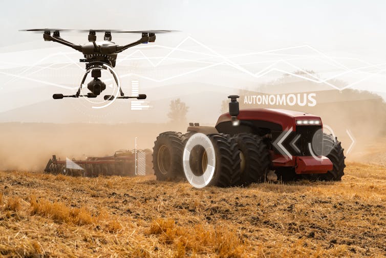 Driverless tractor and drone pass over a field.