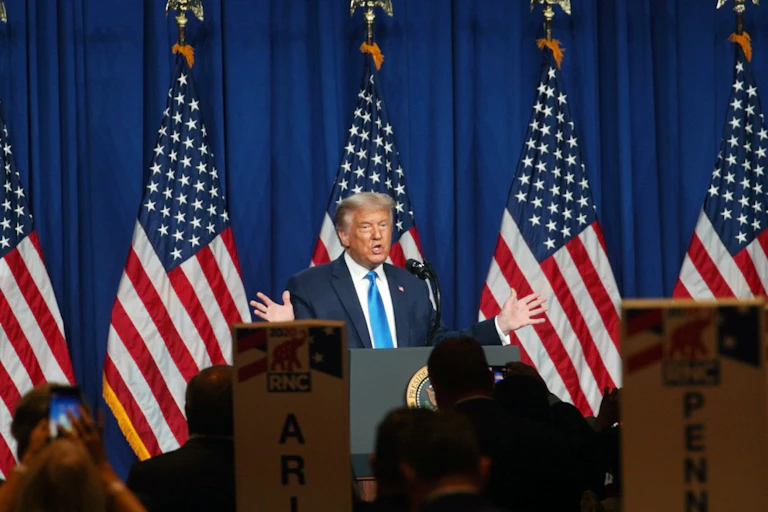 American President Donald Trump, wearing a white shirt and blue tie, lift both hates to emphasise a point at during the Republic Convention.