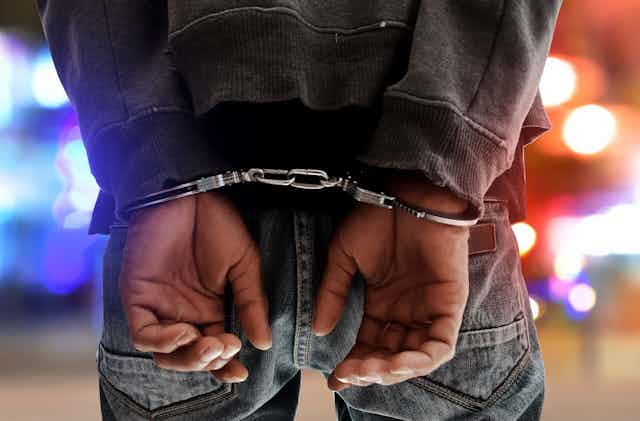 Rear view of the hands and wrists of a man in handcuffs
