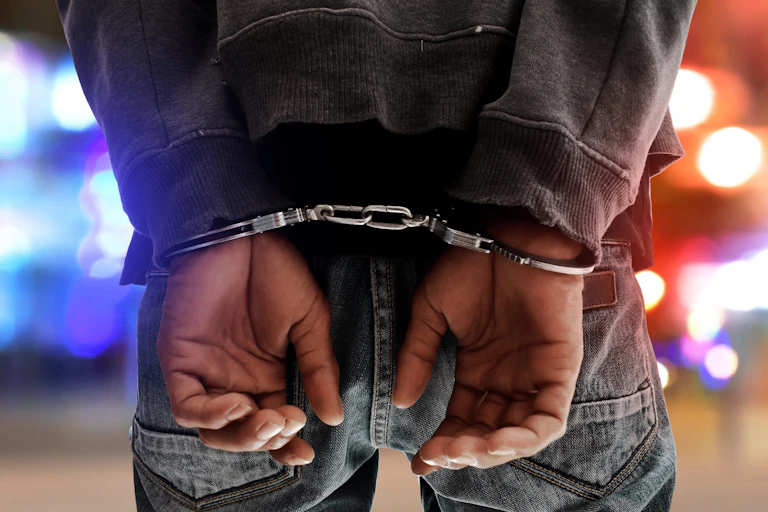 Rear view of the hands and wrists of a man in handcuffs