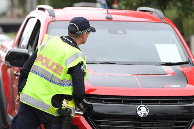A police officer checks a car on the Queensland border