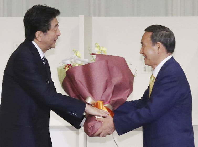 Shizo Abe and Yoshihide Suga holding a bunch of flowers.