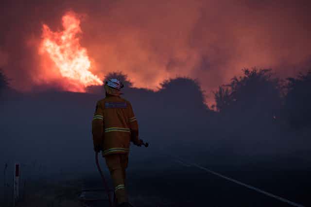 Firefighter moves towards a large blaze.
