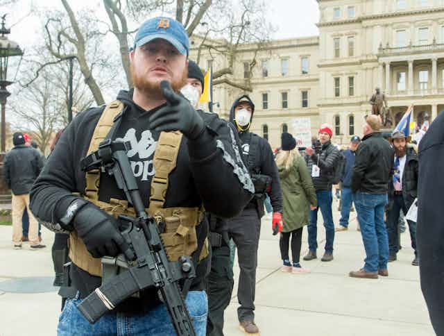 Man carrying rifle stood in front of protestors