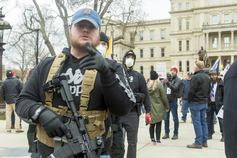 Man carrying rifle stood in front of protestors