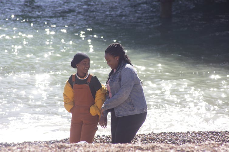 Two teenagers walkingalong a beach.