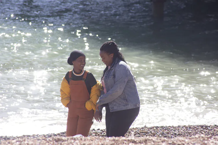 Two teenagers walkingalong a beach.