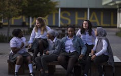 Group of girls in school uniform sitting on a bench.