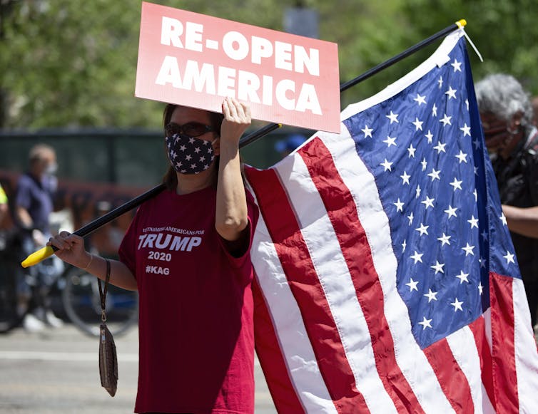 Women in Trump t-shirt holds US flag and 