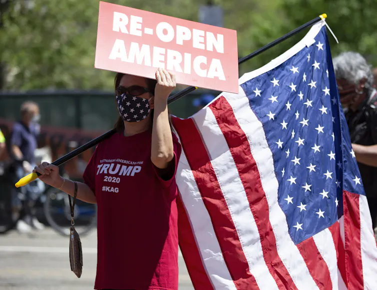 Women in Trump t-shirt holds US flag and