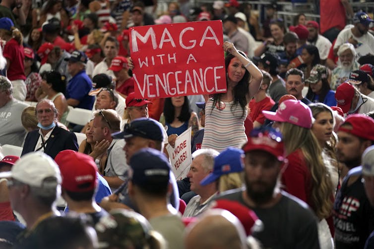 A Trump supporter holds up a sign reading MAGA with a Vengeance at a rally.