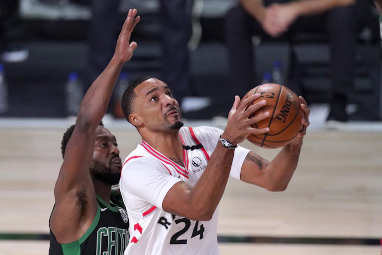 A basketball player prepares to throw the ball with another player behind him.