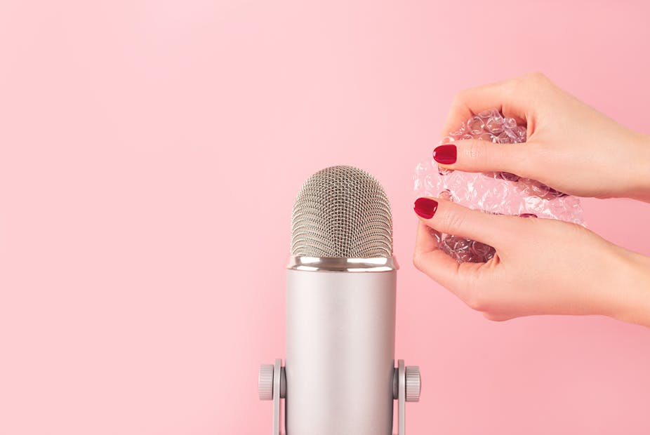 Woman with painted nails pops bubble wrap beside a microphone.