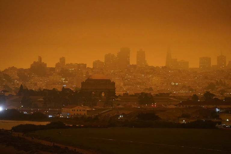 A hazy orange sky hangs over the city.
