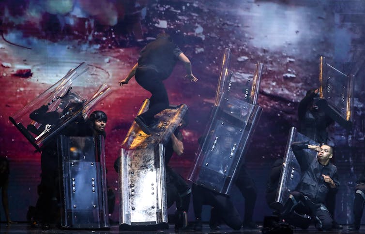 Dancer runs up a police sheild.
