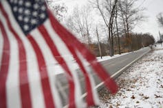 A tattered American flag is flown from a mailbox.
