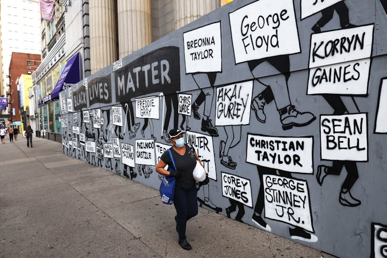 Woman walks past a Black Lives Matter mural
