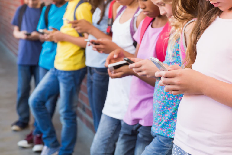 Kids staring at their smartphones.