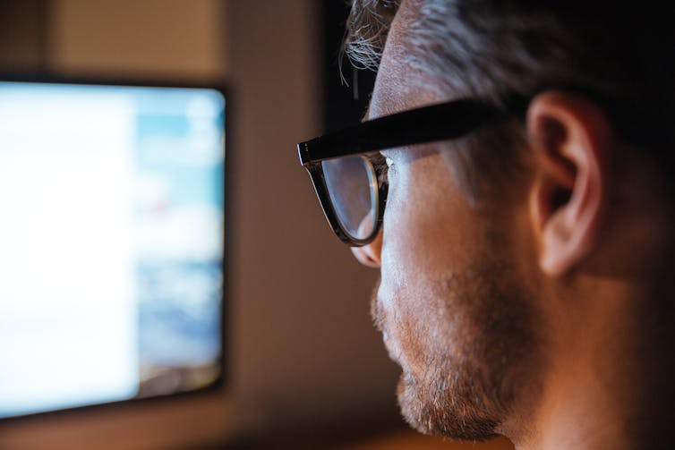 Profile of man looking at blurred computer screen.