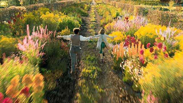 Film still: two children run through a flowering garden