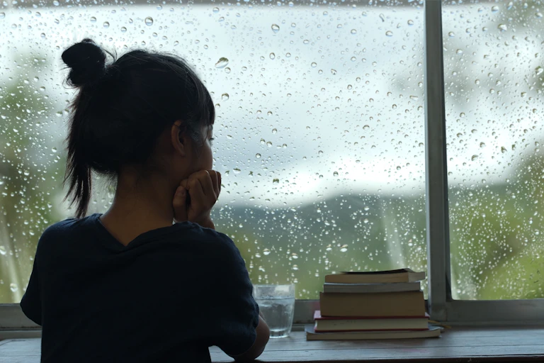 Young girl looking out the window on a rainy day
