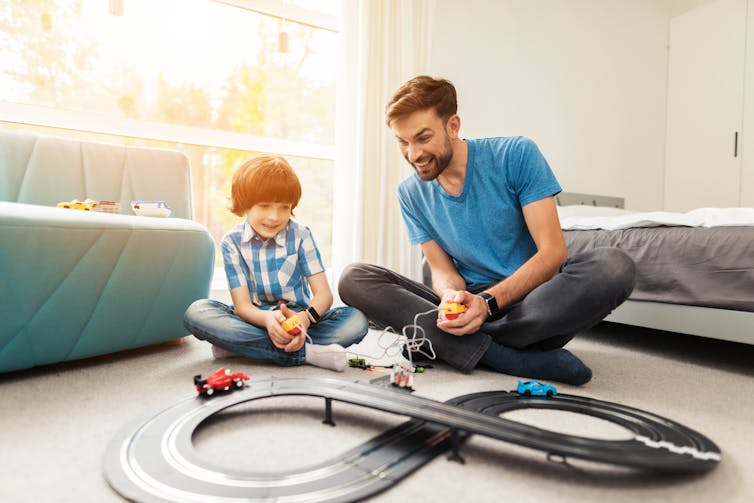 Father and son racing a toy train on a track.