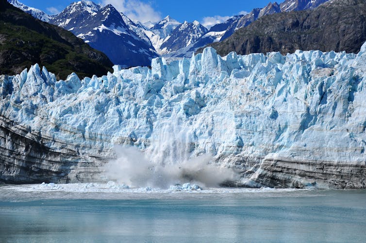 The front of a glacier breaking away and falling into the sea.