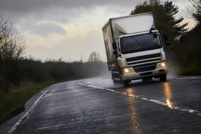 A white lorry speeds down a wet road.