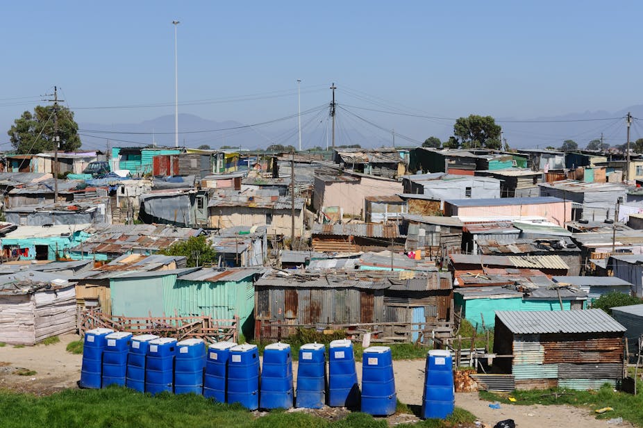 A row of blue, portable toilets on the outskirts of an informal settlement